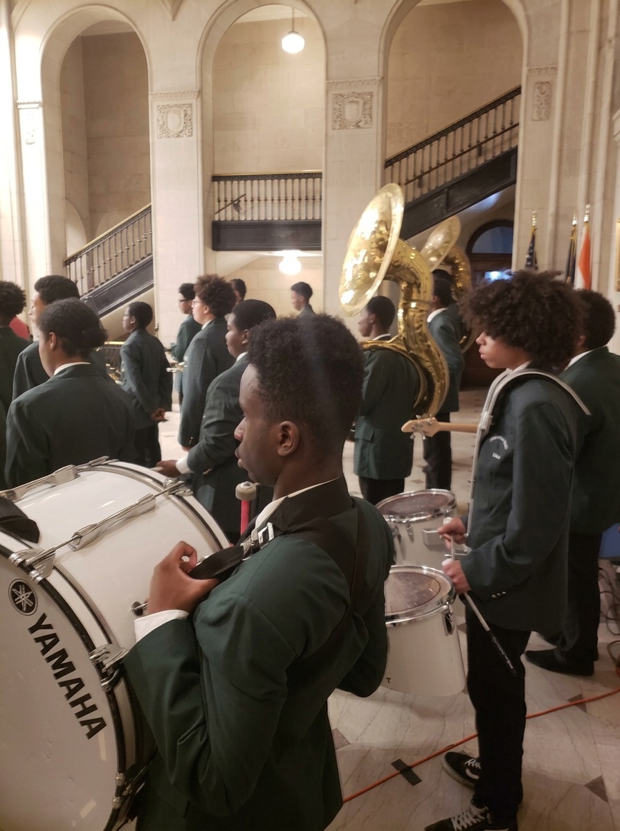 Green Tech High drum line members with bass and snare drums preparing to perform at a community event in Albany, NY