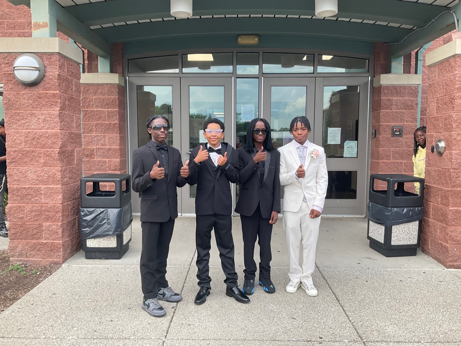 Green Tech High students giving a thumbs up in formal attire at the entrance