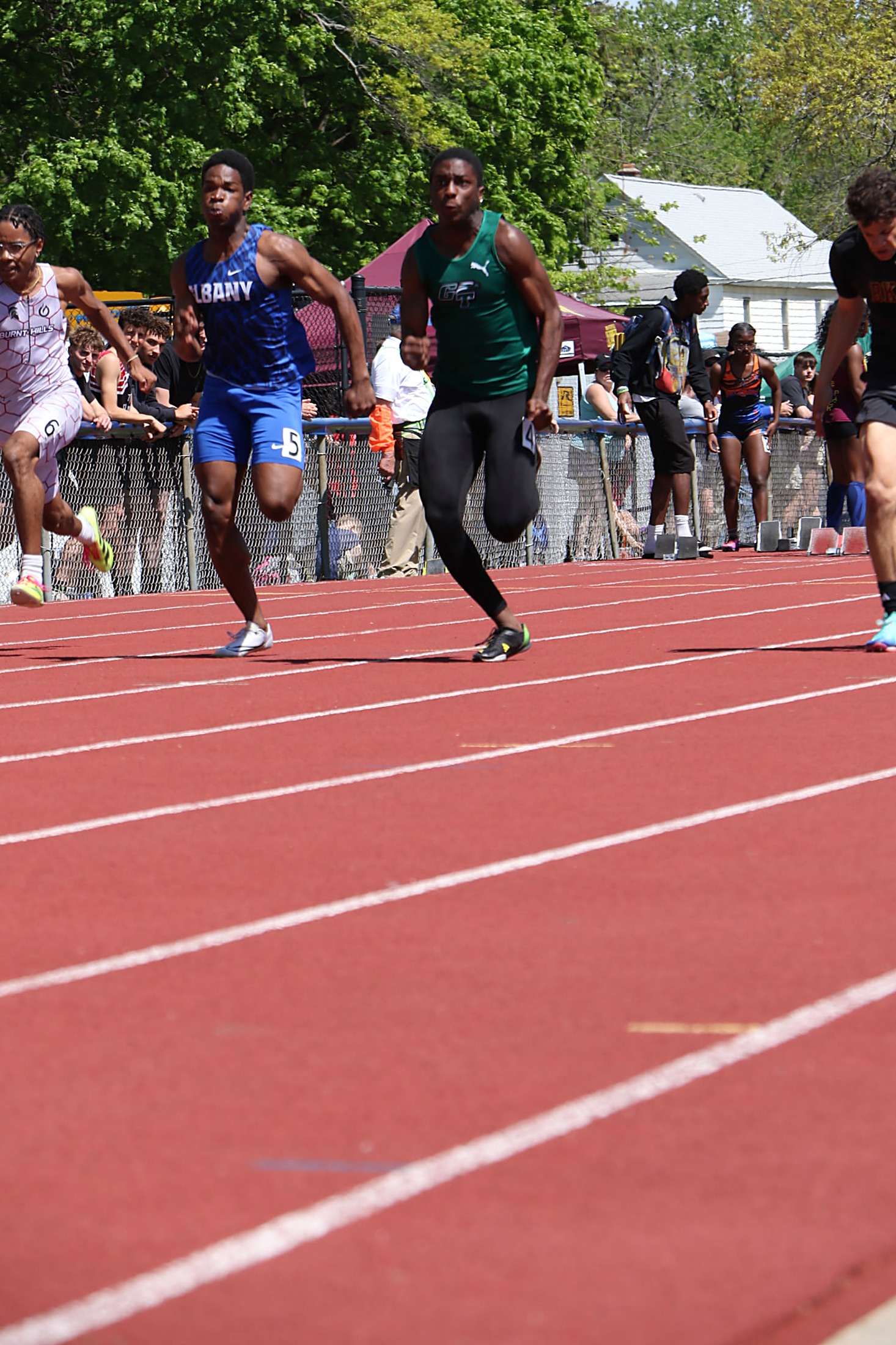Green Tech sprinter in a green GT singlet racing down the track against Albany and Burnt Hills runners