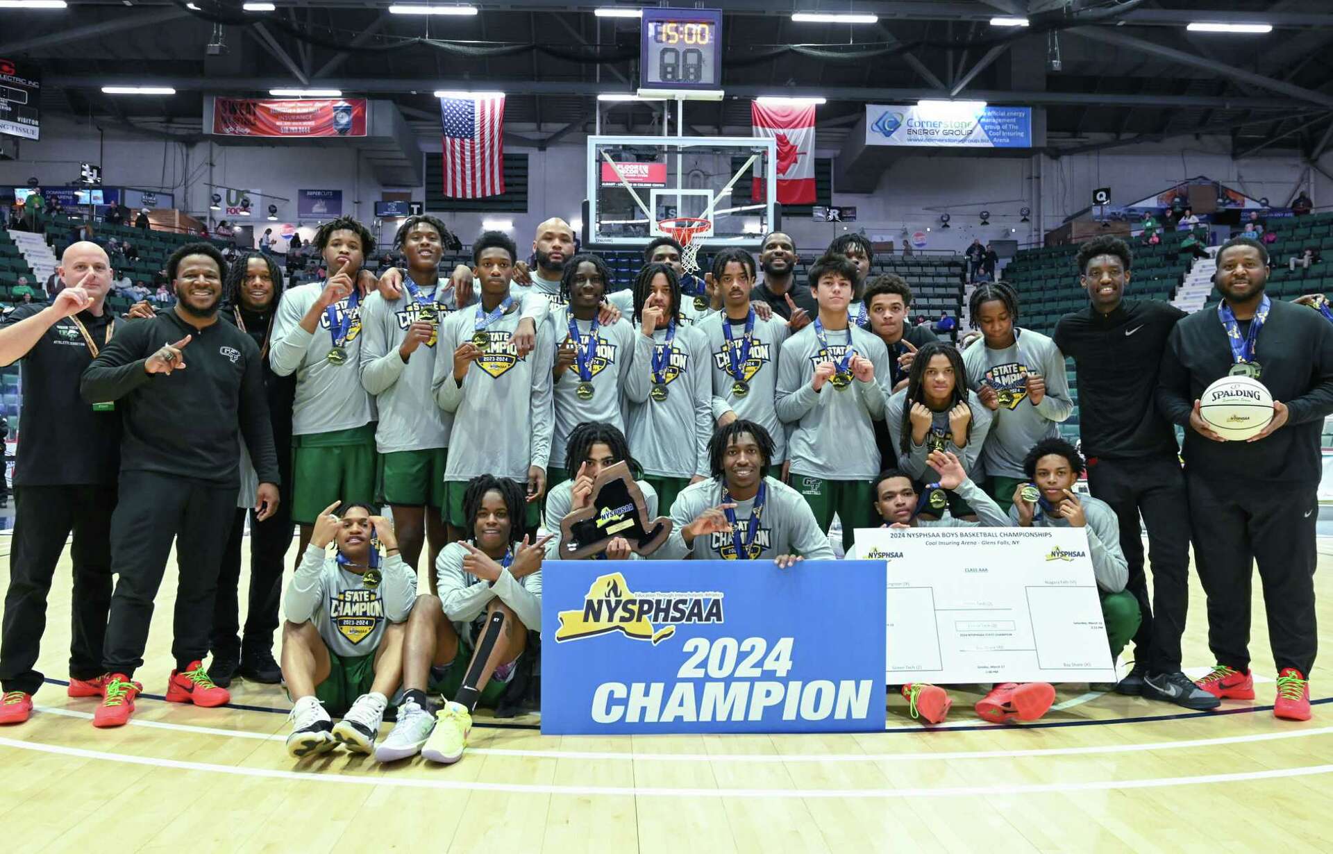 Green Tech High Eagles basketball team celebrating with the 2024 NYSPHSAA Champion banner and state championship medals